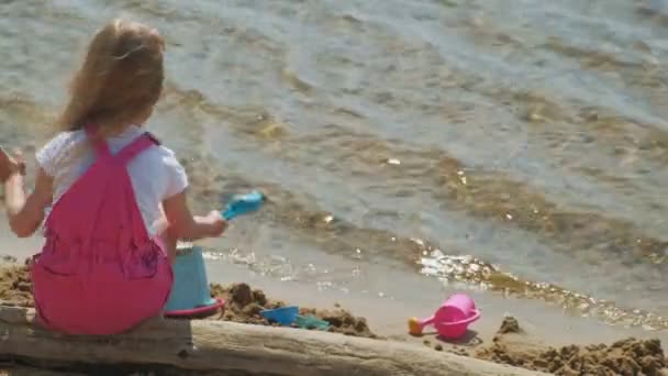 Niños jugando en la playa junto al río en un día soleado — Vídeo de stock
