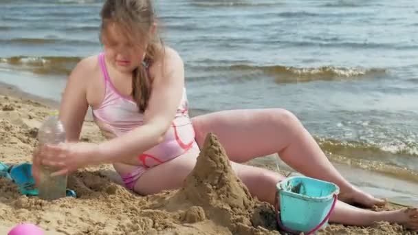 Fille construit un château de sable sur la rive de la rivière — Video