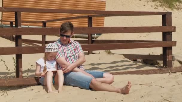 Papá y su hija están usando una tableta al aire libre. Ribera del río — Vídeos de Stock