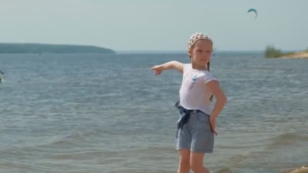 Παιδικό κορίτσι περπατάει δίπλα στο ποτάμι μια καλοκαιρινή μέρα — Αρχείο Βίντεο