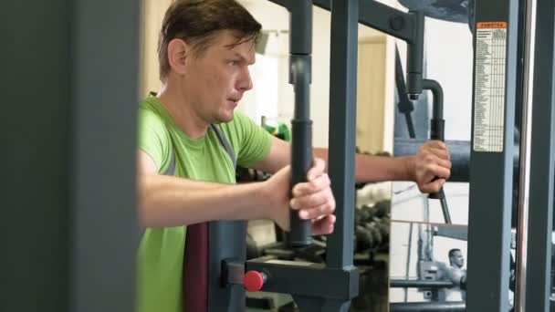 Мужчина делает упражнения на бабочке на тренажере в фитнес-студии. Концепция здорового образа жизни. Фитнес и спорт — стоковое видео
