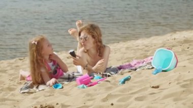 Nehir kıyısındaki anne ve kızı dondurma yiyor. Açık hava rekreasyon