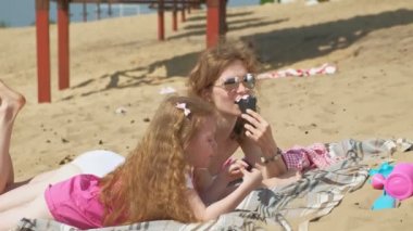 Nehir kıyısındaki anne ve kızı dondurma yiyor. Açık hava rekreasyon