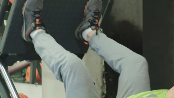 Un homme avec un excès de poids fait pression sur la jambe sur le simulateur dans la salle de gym. Entraînement. Concept de mode de vie sain — Video