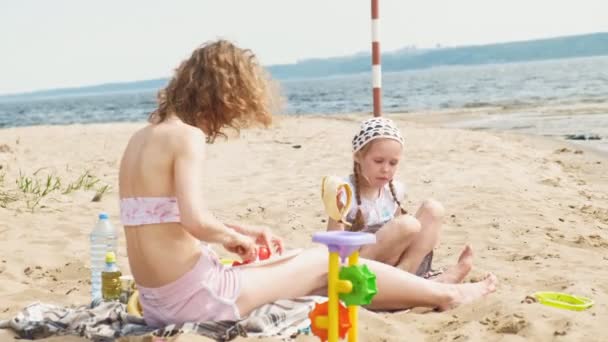 Güneşli bir günde nehir kenarında bir piknik kızı ile anne — Stok video