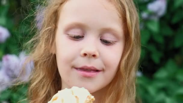 Маленькая девочка ест мороженое на открытом воздухе. Лето — стоковое видео