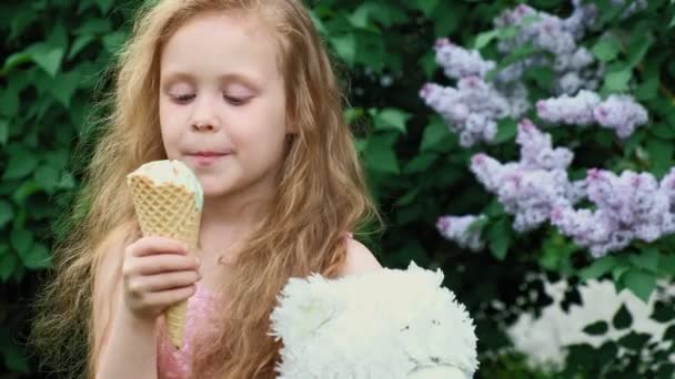 Liten flicka äter glass utomhus. Sommaren — Stockvideo