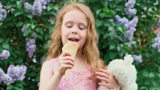 Маленькая девочка ест мороженое на открытом воздухе. Лето — стоковое видео