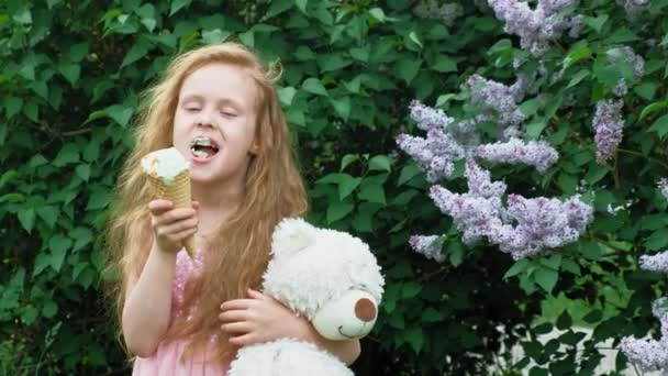 Klein meisje eet ijs buitenshuis. Zomer — Stockvideo