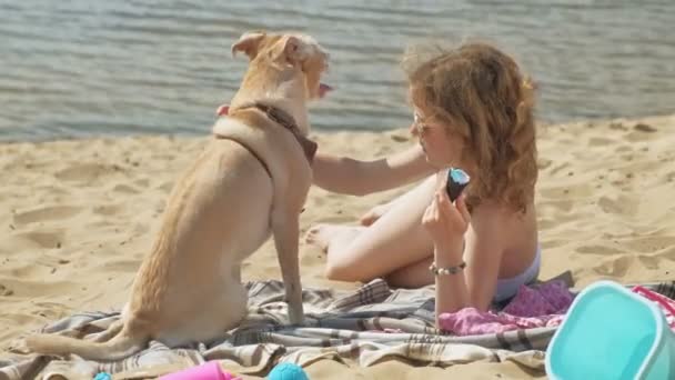 A young woman on the bank of the river is eating ice cream. Outdoor recreation — Stock Video