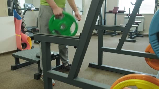 De overgewicht man doet squats met squats met een gewicht schijf voor een barbell. Fitness training. Gezond lifestyle concept — Stockvideo