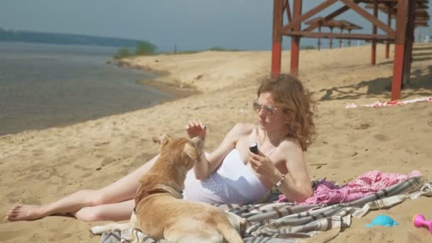 En ung kvinna på stranden av floden äter glass. Friluftsliv — Stockvideo