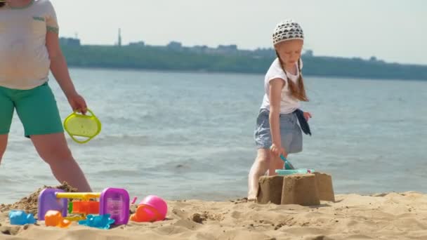 Niños jugando en la playa junto al río en un día soleado — Vídeo de stock