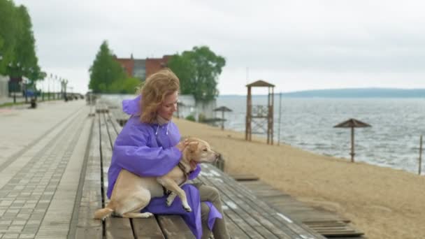 Young woman with a dog on the beach by the river — ストック動画