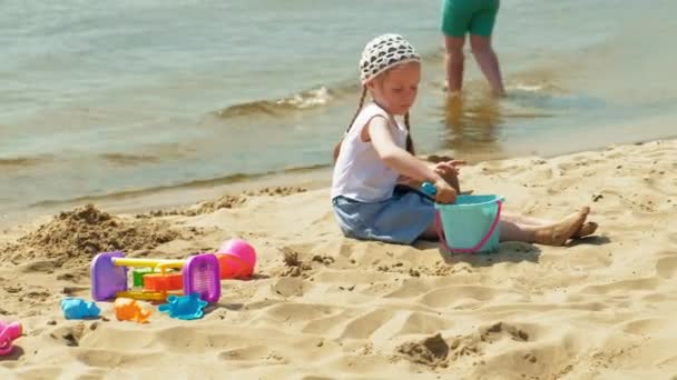 Niños jugando en la playa junto al río en un día soleado — Vídeo de stock