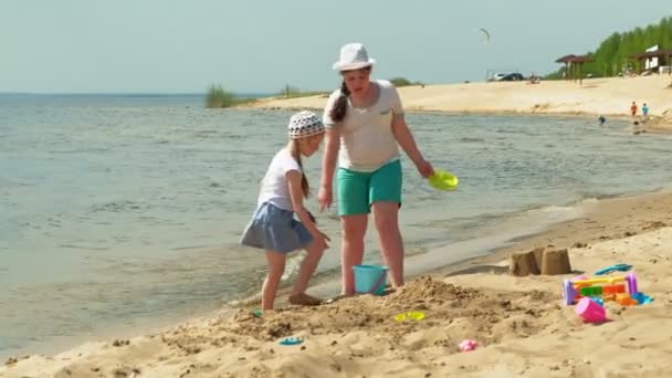 Niños jugando en la playa junto al río en un día soleado — Vídeos de Stock