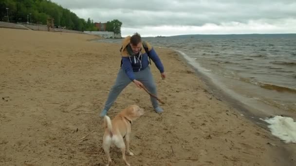 En man leker med en hund vid floden — Stockvideo