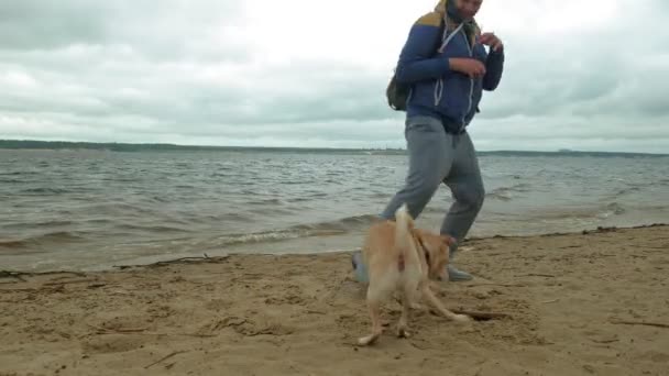 En man leker med en hund vid floden — Stockvideo