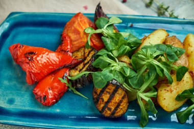 mavi bir tabakta ızgara sebze ve rustik patates