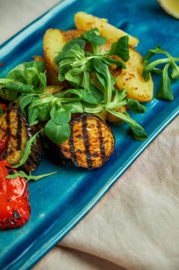 mavi bir tabakta ızgara sebze ve rustik patates