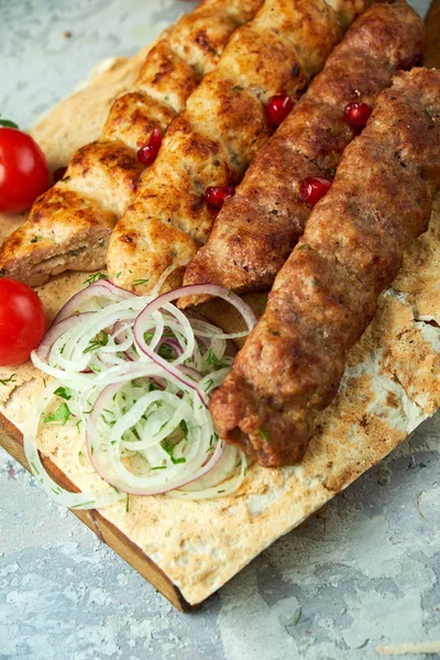 Gri arka planda barbekü ve kebap ile et tabakları