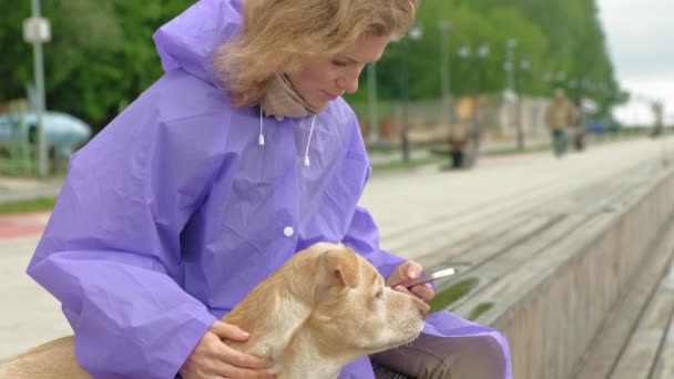 Femeie tânără cu un câine pe plajă lângă râu — Videoclip de stoc