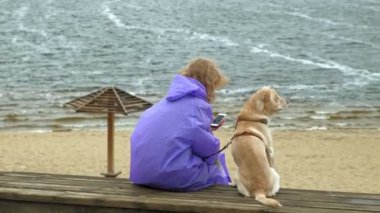 Nehrin kıyısındaki sahilde köpeği olan genç bir kadın.