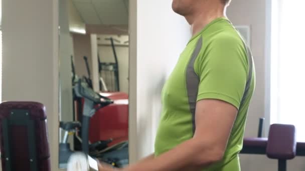 En man gör en bänkpress med hantlar sitter med ett rakt grepp i en fitness Studio — Stockvideo