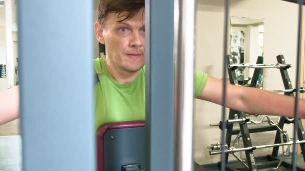 O homem faz um exercício de borboleta no simulador em um estúdio de fitness. O conceito de um estilo de vida saudável. Fitness e Desporto — Vídeo de Stock