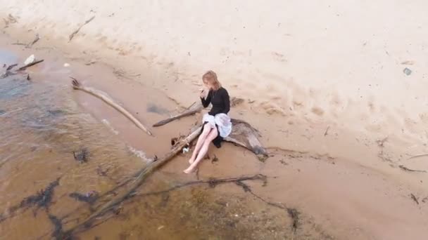 Een jonge vrouw in een jurk loopt langs het strand. Lucht schieten — Stockvideo