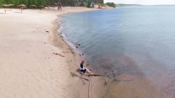 Une jeune femme en robe court le long de la plage. Tournage aérien 