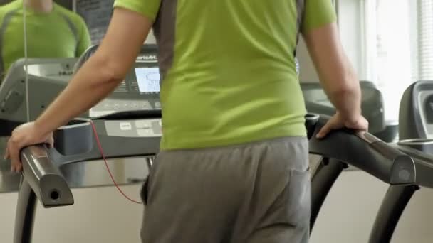 Ένας υπέρβαρων άνθρωπος σε ένα διάδρομο σε ένα γυμναστήριο. Γυμναστήριο. Υγιεινός τρόπος ζωής — Αρχείο Βίντεο