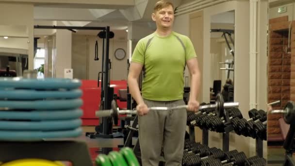 太り過ぎの男はジムに立っている間、ezバーベルを持ち上げます。二頭筋のための運動。フィットネス。健康的なライフスタイル. — ストック動画