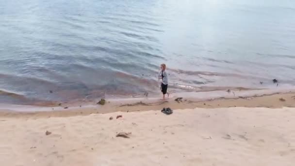 Una joven con un vestido corre por la playa. Disparo aéreo — Vídeos de Stock