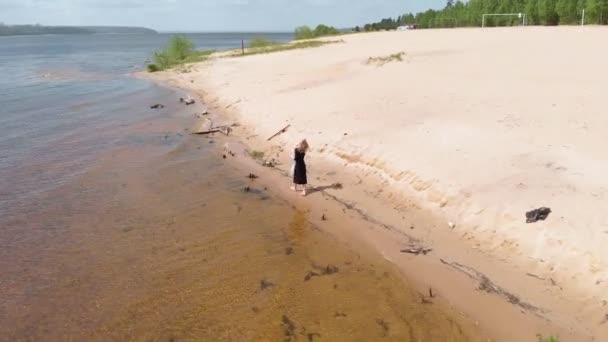 Egy fiatal nő egy ruhában fut végig a parton. Légi hajtás — Stock videók