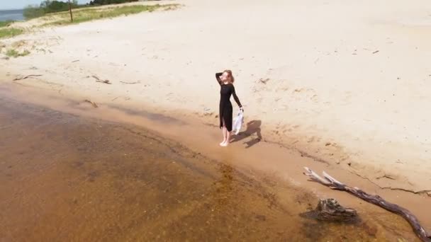 Молодая женщина в платье бежит вдоль пляжа. Аэросъемка — стоковое видео