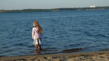 Anne ve kızı, koşmak, nehir kıyısında sahilde kahverengi bir köpek labrador ile oynamak. Havadan çekim