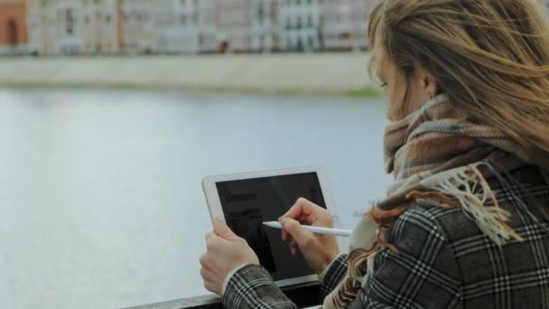 Woman uses tablet outdoors. Spring — Stock Video