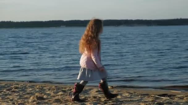 Girl preschool girl  playing with a brown labrador dog on the beach. Spring or cold summer — Stock Video