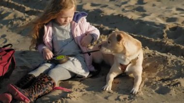 Sahilde kız okul öncesi kız köpek besler. Bahar
