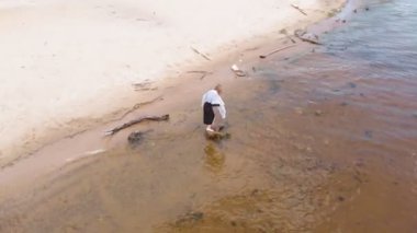 Elbiseli genç bir kadın sahil boyunca koşuyor. Hava çekimi