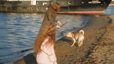Anne ve kızı, koşmak, nehir kıyısında sahilde kahverengi bir köpek labrador ile oynamak. Havadan çekim