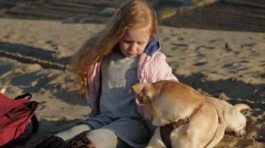 Sahilde kız okul öncesi kız köpek besler. Bahar