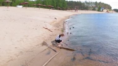 Elbiseli genç bir kadın sahil boyunca koşuyor. Hava çekimi