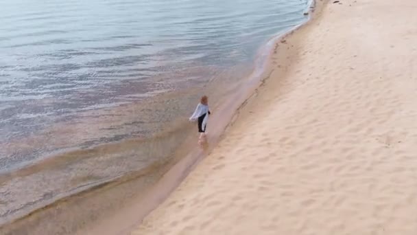 En ung kvinna i en klänning går längs stranden. Flygfotografering — Stockvideo