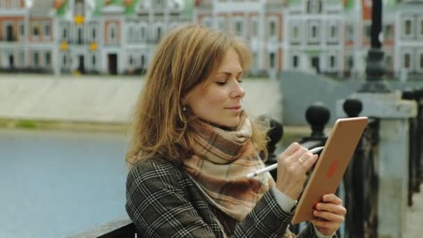 Mujer utiliza tableta al aire libre. Primavera — Vídeos de Stock