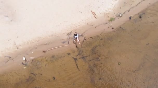 Молодая женщина в платье бежит вдоль пляжа. Аэросъемка — стоковое видео