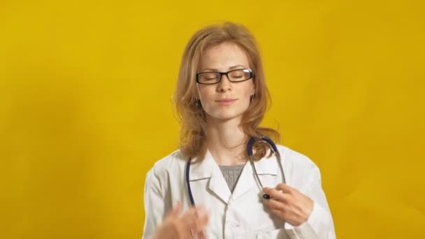 Jonge vrouwelijke dokter. Gele achtergrond. Het begrip "geneeskunde". — Stockvideo