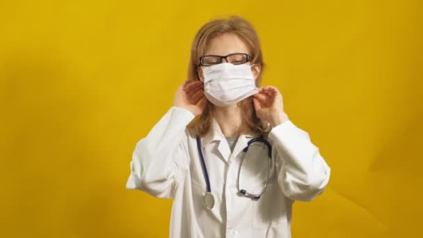 Jonge vrouwelijke dokter. Gele achtergrond. Het begrip "geneeskunde". — Stockvideo