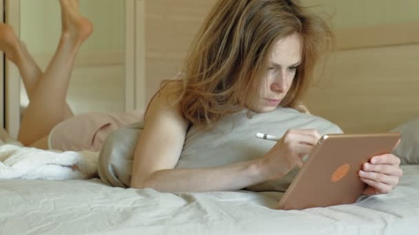 Vrouw in bed met een computer tablet. Goedemorgen. — Stockvideo